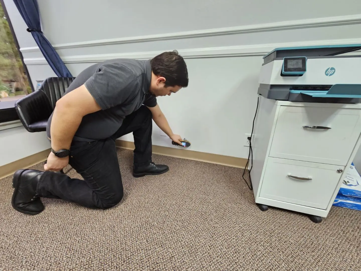 A man kneeling down on the floor in front of a printer.